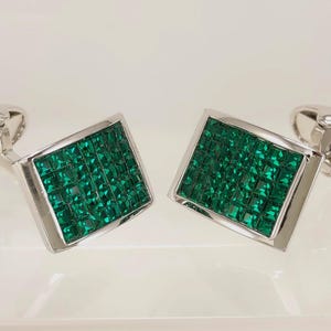 May include: A pair of silver cufflinks with square green gemstone insets.