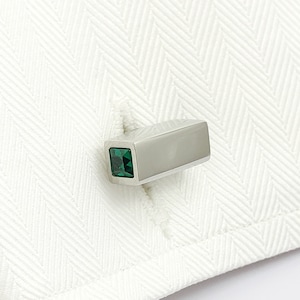 May include: Silver cufflinks with a square green gemstone.