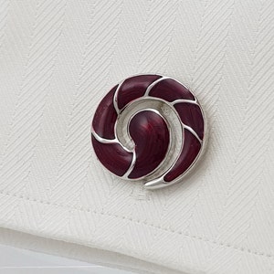 Può includere: Un gemelli d'argento con un design a spirale in smalto rosso.