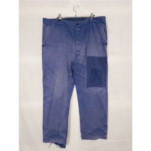 May include: A pair of blue work pants with a patch pocket on the right leg. The pants have a button fly and are made of a durable fabric.