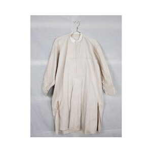 May include: A white linen shirt with a long sleeve and a button-up collar. The shirt has a small pink stain on the front.