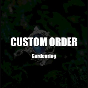May include: Custom order text on a black background with a silver ring with a blue gemstone in the center. The text "Gardenring" is below the ring.