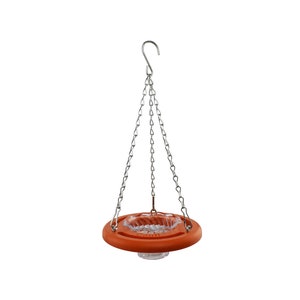 May include: Orange plastic hanging bird feeder with a clear plastic bowl and a silver chain.