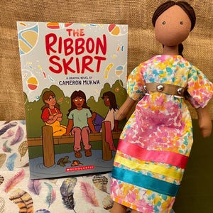 Muñeca con vestido de cinta y falda de cinta, auténtica, de fabricación nativa; libro para lectores no binarios de secundaria.