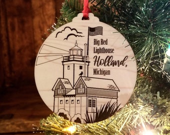 May include: A wooden Christmas ornament featuring a black and white illustration of the Big Red Lighthouse in Holland, Michigan. The ornament is round and has a red ribbon attached.