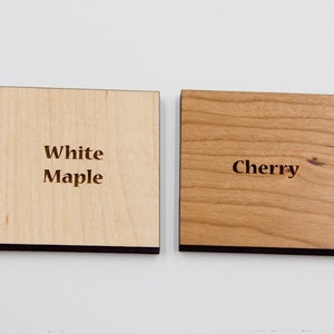 Puede incluir: Dos muestras de madera, una etiquetada como "Maple blanco" y la otra como "Cerezo".