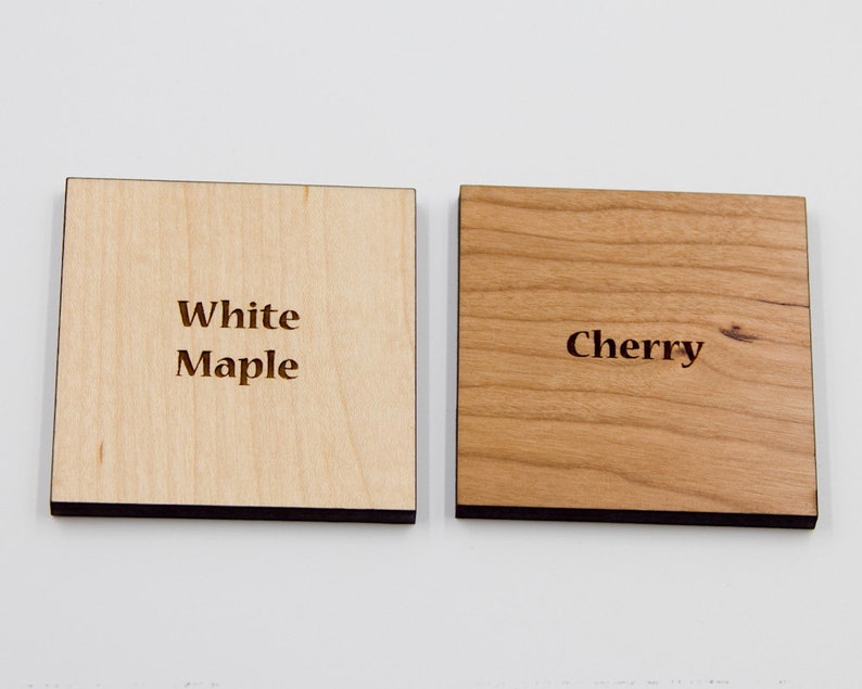 Puede incluir: Dos muestras de madera, una etiquetada como "Maple blanco" y la otra como "Cerezo".