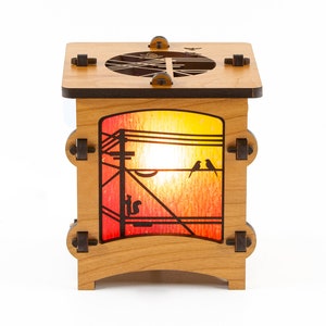 May include: A wooden lamp with a stained glass panel depicting a sunset scene with birds on a power line. The lamp has a warm, inviting glow.