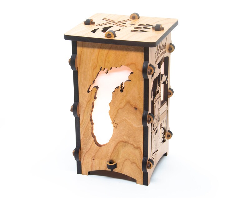 Puede incluir: Una l&aacute;mpara de madera con un recorte del estado de Michigan y el texto "Holland, The City of Windmills" en el lateral. La l&aacute;mpara est&aacute; iluminada desde el interior, proyectando un c&aacute;lido resplandor.