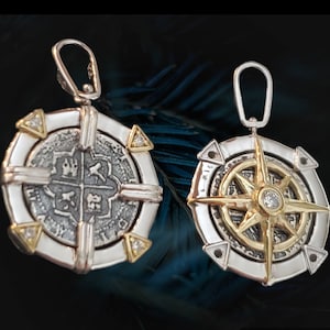May include: Two silver and gold pendants with a compass and a coin design. Both pendants have a silver frame with gold accents and a clear gemstone in the center.