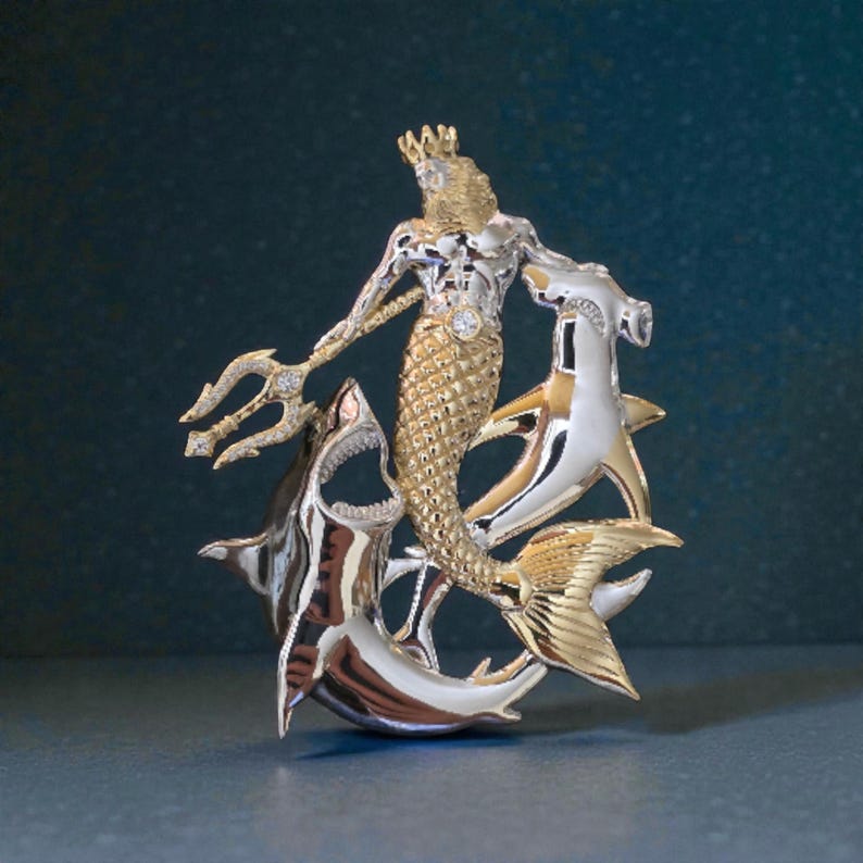 May include: A detailed, two-tone metal sculpture of a merman with a trident, crown, and a diamond accent. The merman is surrounded by two sharks. The sculpture is gold and silver in color.
