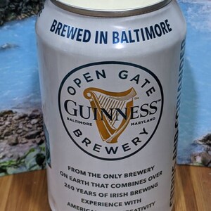 May include: A white candle in a Guinness Brewery beer can. The can features the brewery's logo and text that reads "BREWED IN BALTIMORE" and "FROM THE ONLY BREWERY ON EARTH THAT COMBINES OVER 260 YEARS OF IRISH BREWING EXPERIENCE WITH AMERICAN BEER CREATIVITY."