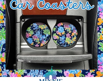 May include: Two round car coasters with a colorful floral and Disney character print. The coasters are in the cup holders of a car. The text "Car Coasters" is above the coasters. The text "Minnie Jenities Magic Market" is below the coasters.