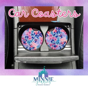 May include: Two round car coasters with a floral and cartoon character design. The coasters are in a car cup holder. The coasters are pink, blue, and green. The text "Car Coasters" is at the top of the image. The text "Minnie Jenities Magic Market" is at the bottom of the image.