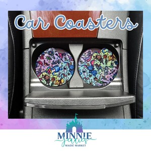 May include: Two colorful car coasters featuring a whimsical design with cartoon characters and a rainbow color scheme. The coasters are in a car cup holder.