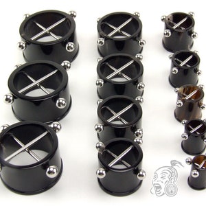 Può includere: Un set di dieci tappi in corno nero con accenti in metallo argentato. Ogni tappo ha un design a croce ed è disponibile in diverse dimensioni.