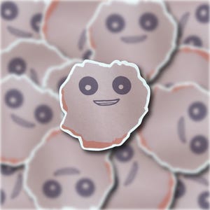 May include: A sticker of a cartoon character with a pink and white body, black eyes, and a smiling mouth. The character is surrounded by other stickers of the same character.