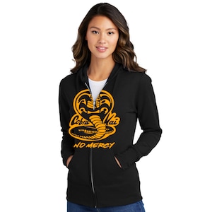 May include: Black zip-up hoodie with a yellow Cobra Kai logo and the words "No Mercy" printed on the front.