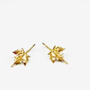 May include: A pair of gold-toned earrings with a maple leaf design.