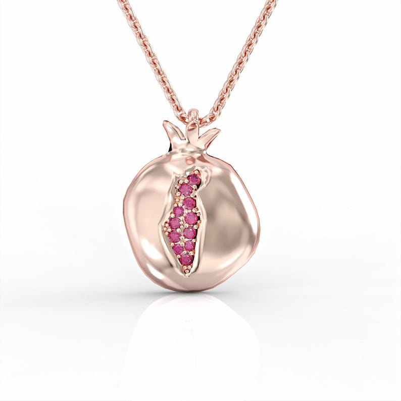 Puede incluir: Un collar de oro rosa con un colgante de granada. El colgante est&aacute; decorado con una fila de piedras preciosas rosas.