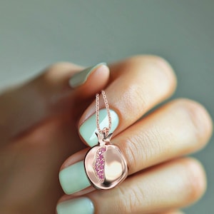 Puede incluir: Un collar de oro rosa con un colgante de granada. El colgante est&aacute; lleno de piedras preciosas rosas.