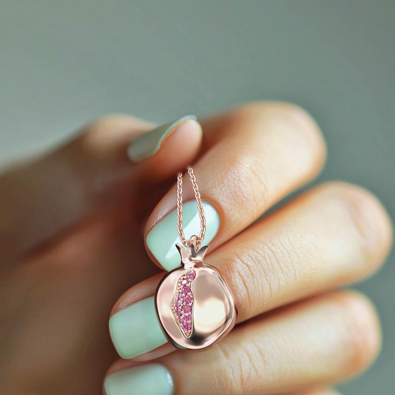 Puede incluir: Un collar de oro rosa con un colgante de granada. El colgante est&aacute; lleno de piedras preciosas rosas.