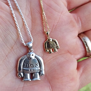 Puede incluir: Dos collares de plata y oro con colgantes que representan una figura de dibujos animados con la palabra "אדם" escrita en el pecho. La figura lleva un sombrero y una barba.