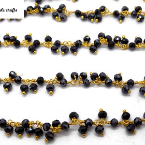 May include: Strands of black faceted beads are strung on gold-colored wire. The beads are clustered together, creating a textured look. The image includes the text "India beads crafts" in the upper left corner.