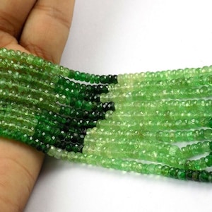May include: Strands of faceted green beads, varying in shades from light to dark, creating a gradient effect. The beads are strung together, forming multiple rows. The beads are small and appear to be gemstones.