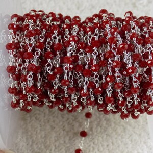 May include: A length of red, faceted beads strung on silver-coloured wire. The beads are a deep red colour and are closely spaced. The wire is visible between the beads, creating a delicate, intricate pattern.