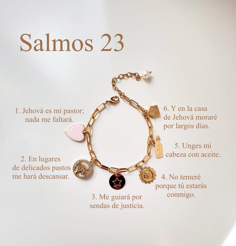 Puede incluir: Pulsera dorada con dijes variados, incluyendo un coraz&oacute;n, una estrella y un sol. La pulsera tiene una perla al final y texto en espa&ntilde;ol: "Salmos 23". Los dijes est&aacute;n detallados con dise&ntilde;os intrincados y texto.