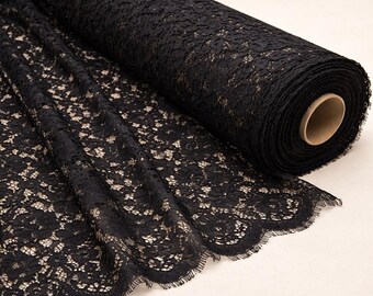 May include: A roll of black lace fabric with a floral pattern. The lace is partially unrolled, revealing the intricate design and scalloped edge. The fabric is a deep black color.