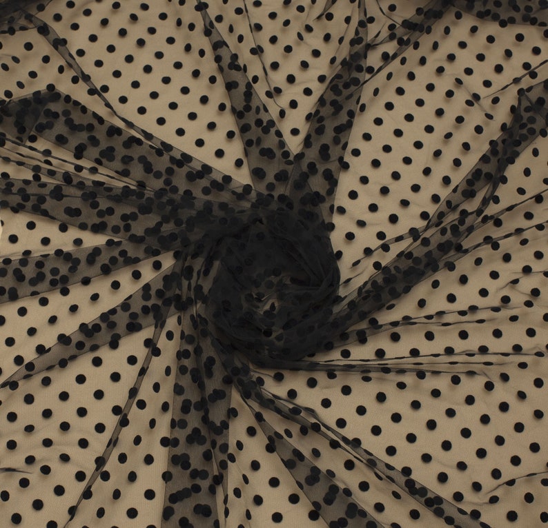 May include: Black sheer fabric with black polka dots. The fabric is textured and has a soft, delicate feel.