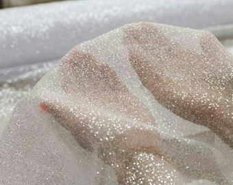 May include: White sheer fabric with a sparkly, glittery texture. The fabric is soft and delicate, perfect for crafting or adding a touch of sparkle to any project.