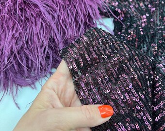 May include: Purple feather trim with black sequins and a pink iridescent sheen. The sequins are sewn onto a mesh fabric.