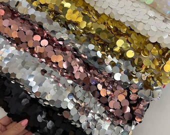 Puede incluir: Una colección de tela de lentejuelas en varios colores, incluyendo blanco, dorado, plateado, oro rosa y negro. Las lentejuelas son redondas y están densamente empaquetadas, creando un efecto brillante. La tela se utiliza probablemente para ropa o decoración.