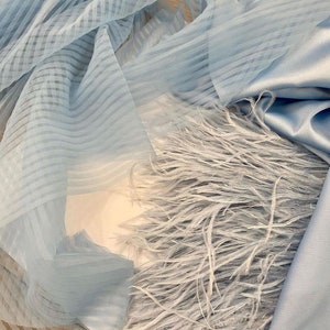 May include: A light blue fabric with a striped pattern and a layer of light blue feathers.