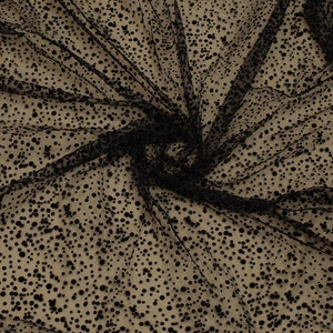 May include: Black tulle fabric with small black polka dots. The fabric is sheer and has a soft, delicate texture.