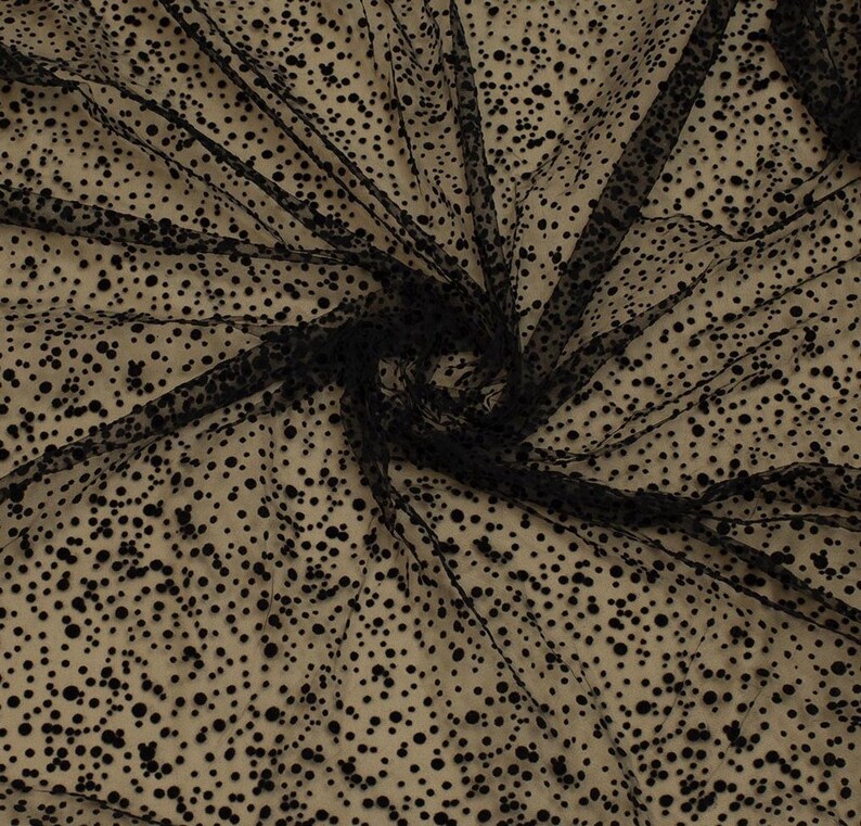 May include: Black tulle fabric with small black polka dots. The fabric is sheer and has a soft, delicate texture.