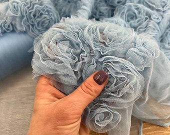 May include: Light blue fabric with a 3D rose design. The fabric is soft and delicate, perfect for adding a touch of elegance to any project.