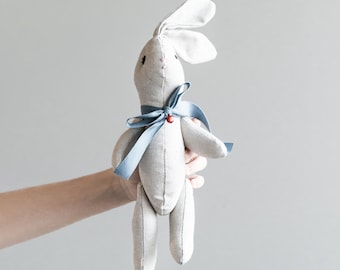 bunny-shaped plush toy with blue bow and red bell. Made to order.