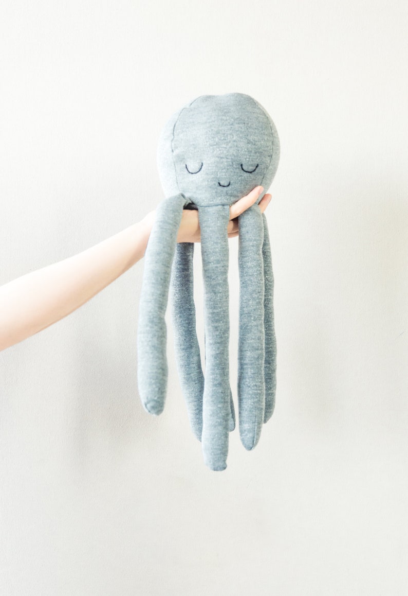 May include: A grey plush octopus toy with a smiling face and closed eyes. The octopus has five long tentacles.