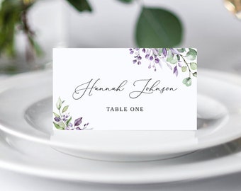 Puede incluir: Tarjeta de lugar blanca con un diseño floral morado y verde. El texto en la tarjeta dice "Hannah Johnson" y "Mesa Uno".