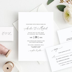 Op de afbeelding: Een witte huwelijksuitnodigingsset met kalligrafie-lettertype. De uitnodigingskaart bevat de namen Amelia en Michael, de datum zaterdag 28 augustus 2021 en de tijd 18:00 uur. De RSVP-kaart bevat een regel voor gasten om hun aanwezigheid aan te geven en een sectie voor maaltijdkeuzes.