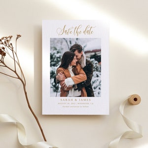 Puede incluir: Tarjeta de guardar la fecha con una foto de una pareja en un entorno nevado. La tarjeta es blanca con letras doradas y dice "Save the date" en la parte superior. Los nombres de la pareja son Sarah & James, y la fecha es el 28 de agosto de 2023. La ubicación es Woodside, CA. El texto en la parte inferior dice "Invitación formal a seguir."
