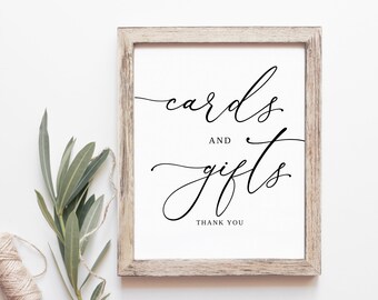 May include: A white sign with a wooden frame, the sign says "cards and gifts" in black cursive writing with "thank you" below in smaller font.
