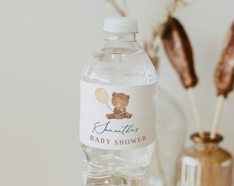 May include: A clear plastic water bottle with a white label. The label has a cartoon brown bear holding a yellow balloon and the text "Samantha's Baby Shower".