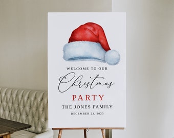 May include: A white sign with a red and white Santa hat illustration. The sign says "Welcome to our Christmas Party, The Jones Family, December 23, 2023".