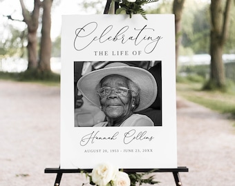 May include: A white sign with black text and a black and white photo of a woman. The sign reads "Celebrating the life of Hannah Collins August 20, 1953 - June 23, 20XX".