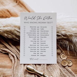Peut inclure: Une carte blanche avec le texte "Would She Rather" et "Who Knows Mommy Best?" La carte contient une liste de 14 questions avec deux choix pour chaque question. Les choix sont séparés par le mot "or". La carte a une ligne en bas pour "Total Correct".